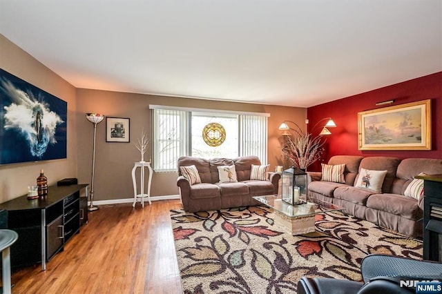 living area featuring baseboards and light wood finished floors