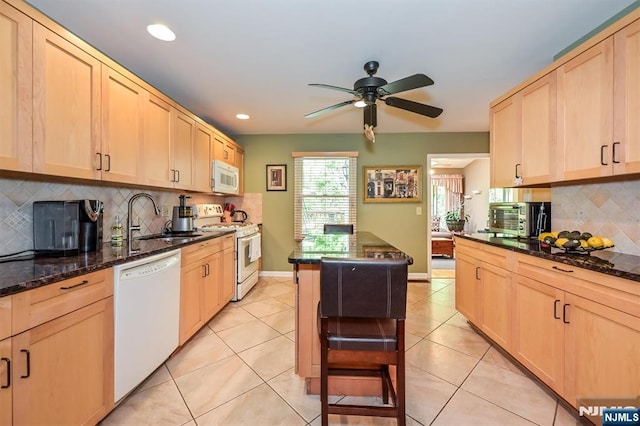 kitchen featuring a ceiling fan, tasteful backsplash, a sink, light brown cabinets, and white appliances