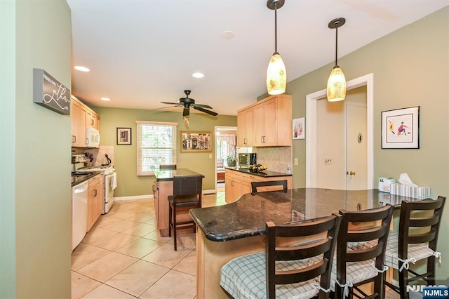 kitchen featuring light brown cabinetry, decorative backsplash, a center island, and white appliances