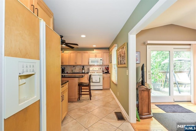 kitchen featuring light brown cabinetry, dark countertops, white appliances, tasteful backsplash, and visible vents