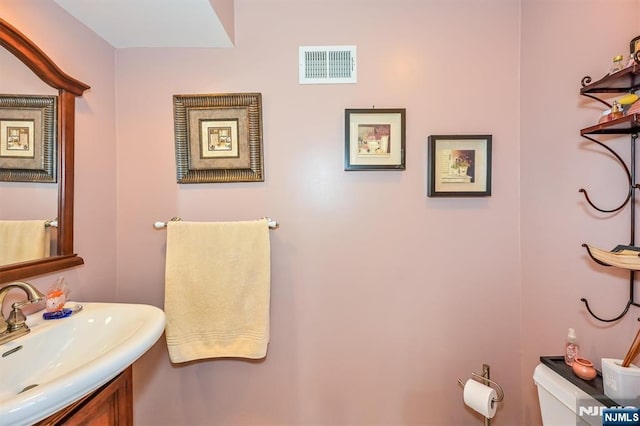 half bathroom featuring toilet, visible vents, and a sink