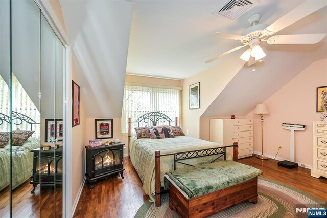 bedroom with visible vents, lofted ceiling, wood finished floors, baseboards, and ceiling fan