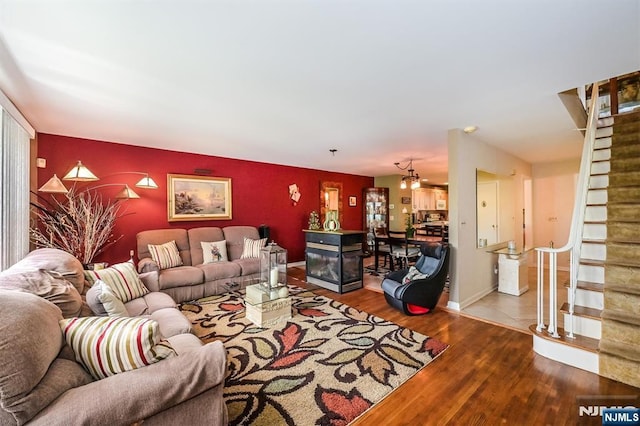living area featuring baseboards, an accent wall, wood finished floors, and stairway