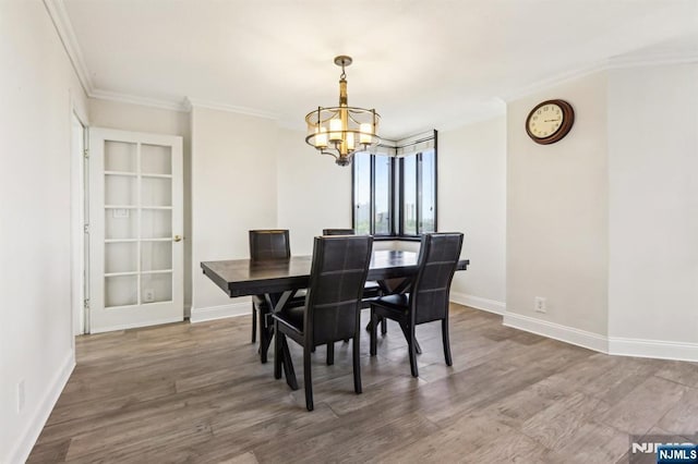 dining area featuring baseboards, a notable chandelier, ornamental molding, and wood finished floors