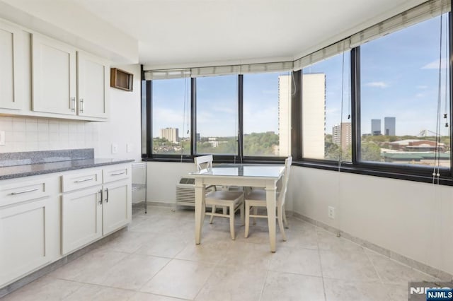 dining room featuring baseboards, a view of city, and light tile patterned flooring
