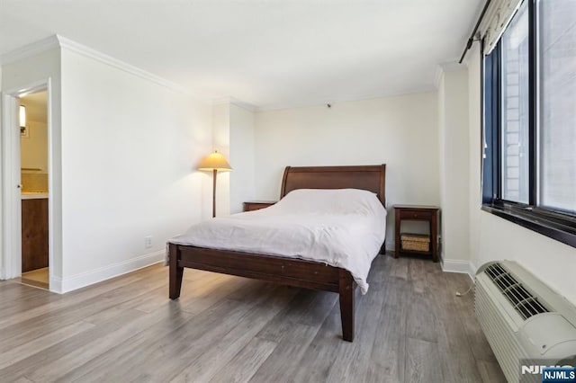bedroom featuring crown molding, baseboards, an AC wall unit, and wood finished floors