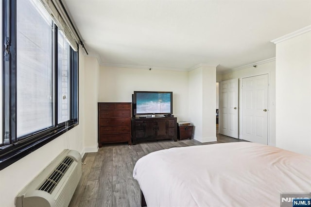 bedroom with an AC wall unit, ornamental molding, wood finished floors, and multiple windows