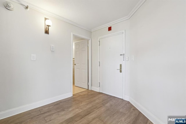 spare room with crown molding, baseboards, and wood finished floors