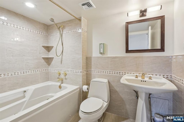 bathroom with visible vents, tub / shower combination, toilet, and tile walls