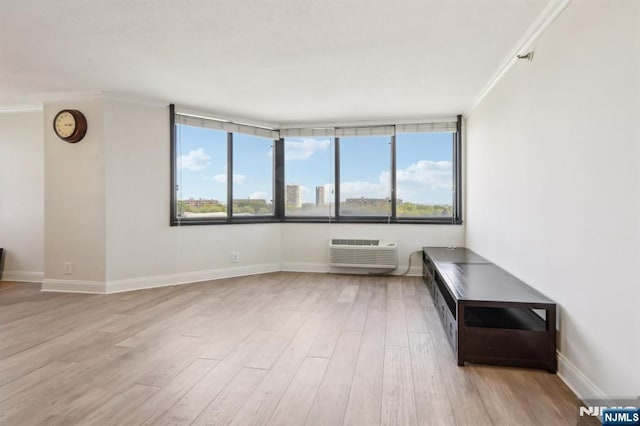 unfurnished room featuring baseboards, ornamental molding, a wall unit AC, and wood finished floors