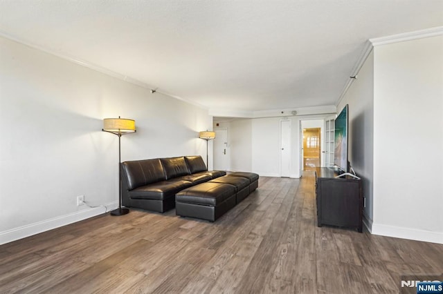 living area featuring baseboards, ornamental molding, and wood finished floors