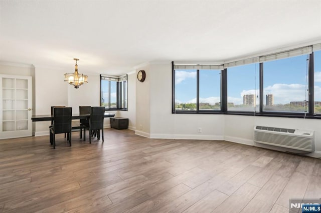 living room with an inviting chandelier, a healthy amount of sunlight, wood finished floors, and a wall mounted air conditioner