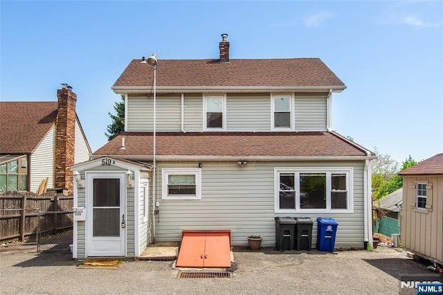 516 5th St, Carlstadt, NJ 07072 - back of house with a storage unit, an outdoor structure, fence, and a shingled roof