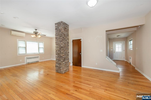 516 5th St, Carlstadt, NJ 07072 - unfurnished living room featuring light wood-style floors, radiator, a wall unit AC, and decorative columns