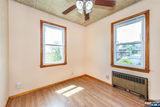516 5th St, Carlstadt, NJ 07072 - empty room with baseboards, light wood finished floors, radiator heating unit, and a wealth of natural light
