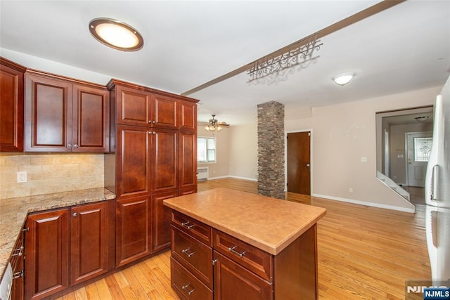 516 5th St, Carlstadt, NJ 07072 - kitchen featuring reddish brown cabinets, light countertops, a center island, light wood-style flooring, and backsplash
