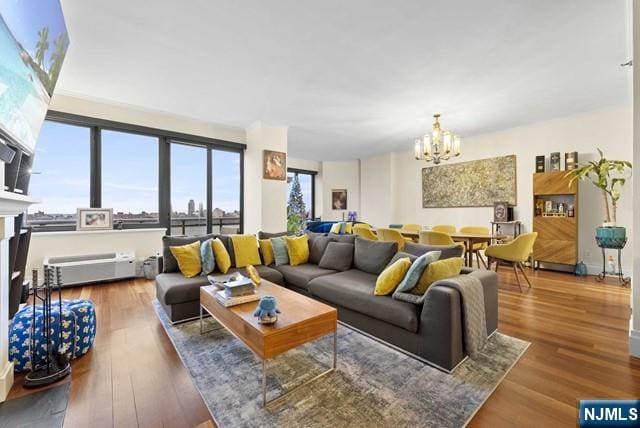 living room with a notable chandelier, a fireplace with flush hearth, and wood finished floors