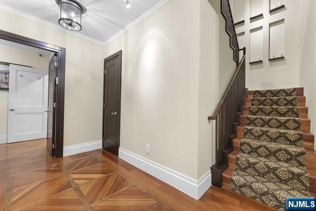 stairway with crown molding and baseboards