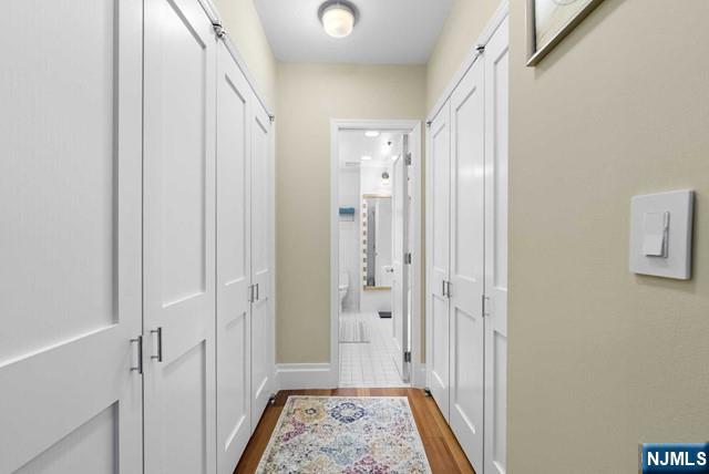 corridor featuring baseboards and dark wood-type flooring