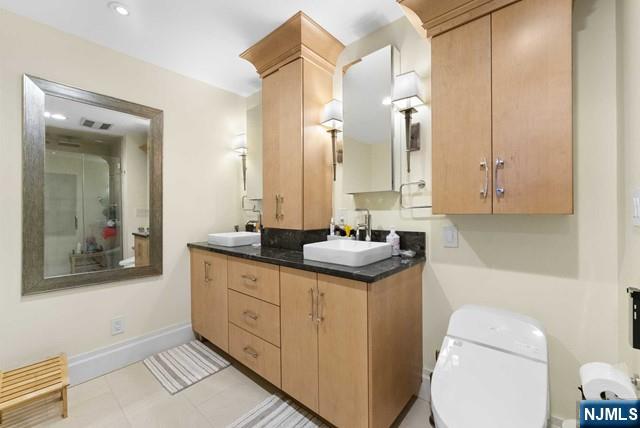 bathroom featuring double vanity, visible vents, a sink, baseboards, and toilet