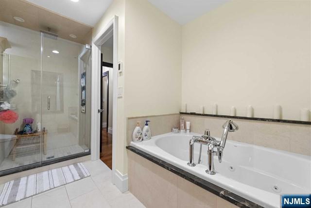 bathroom with a jetted tub, tile patterned flooring, and a stall shower