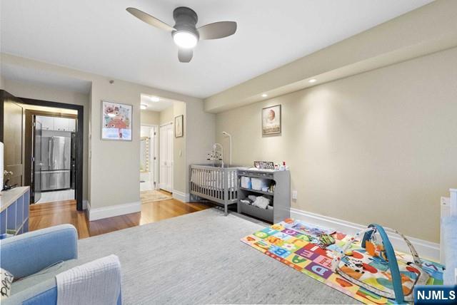 bedroom with a ceiling fan, baseboards, and wood finished floors