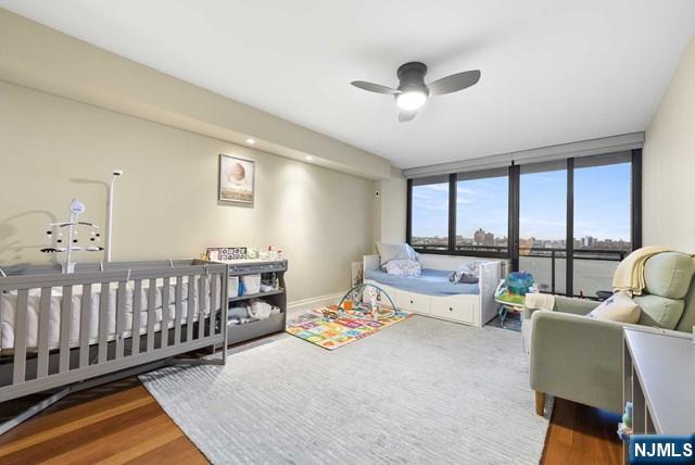 bedroom featuring expansive windows, a ceiling fan, and wood finished floors