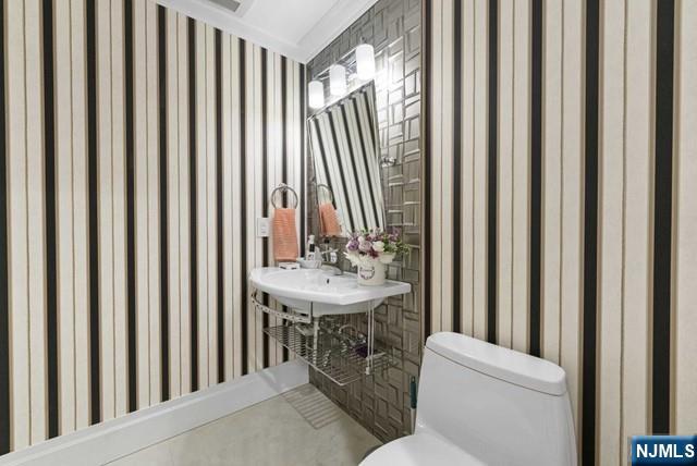 bathroom with toilet and wallpapered walls