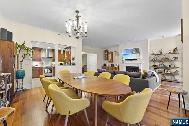dining room featuring a chandelier, ornamental molding, wood finished floors, and a fireplace