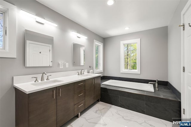 full bathroom with double vanity, a sink, marble finish floor, and a bath
