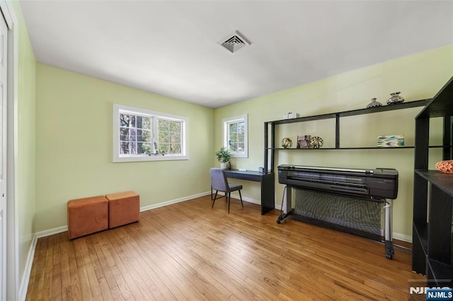 living area with visible vents, baseboards, and hardwood / wood-style floors