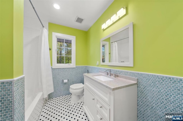 full bathroom featuring visible vents, wainscoting, toilet, tile walls, and tile patterned floors