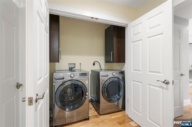 washroom with visible vents, light wood finished floors, cabinet space, and washer and clothes dryer
