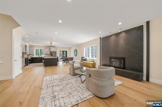 living area featuring light wood-type flooring, baseboards, a fireplace, and recessed lighting