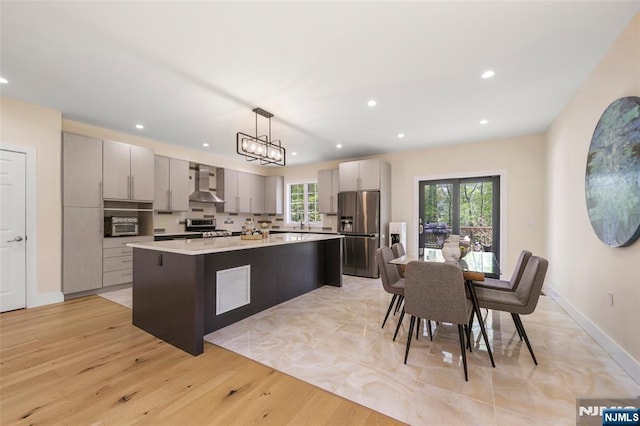 kitchen featuring wall chimney range hood, recessed lighting, light countertops, gray cabinetry, and stainless steel appliances