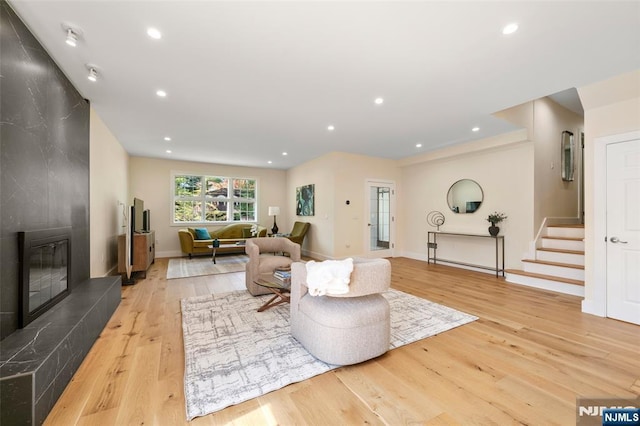 living room with a large fireplace, stairway, baseboards, light wood-style floors, and recessed lighting