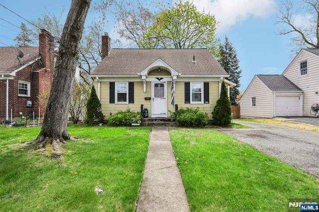 bungalow-style house featuring a chimney, driveway, and a front lawn