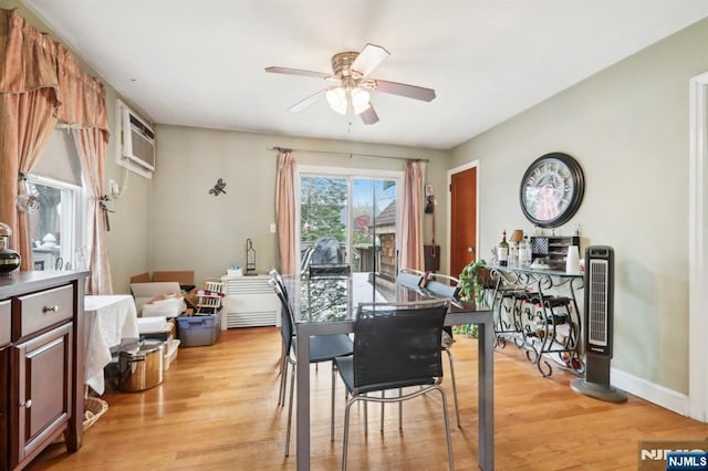 dining area with baseboards, a ceiling fan, light wood-type flooring, and a wall mounted air conditioner