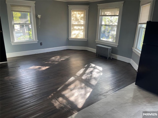 empty room with radiator, baseboards, ornamental molding, and wood finished floors