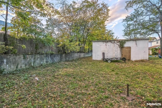 view of yard with fence, an outbuilding, and a storage unit