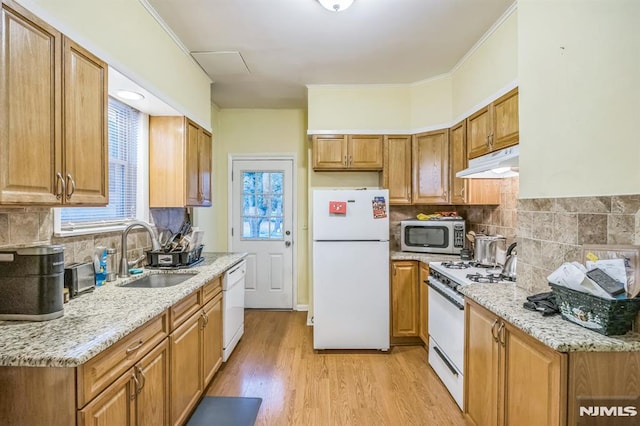 kitchen featuring white appliances, under cabinet range hood, tasteful backsplash, a sink, and light wood finished floors