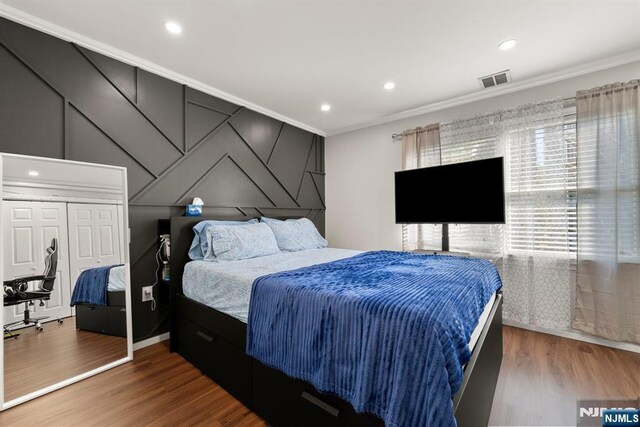 bedroom with ornamental molding, wood finished floors, and visible vents