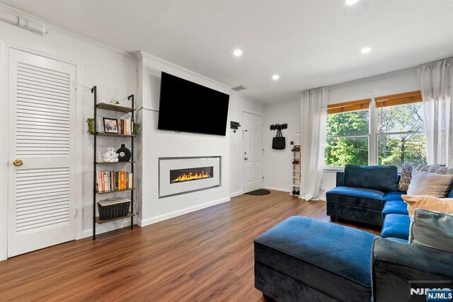living area with ornamental molding, a lit fireplace, recessed lighting, and wood finished floors