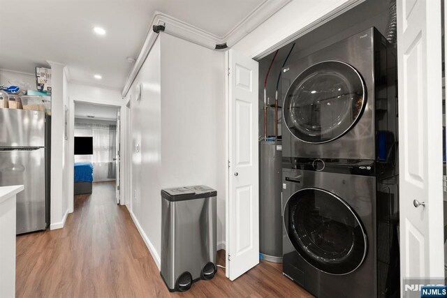 laundry room with laundry area, ornamental molding, wood finished floors, stacked washer / dryer, and recessed lighting