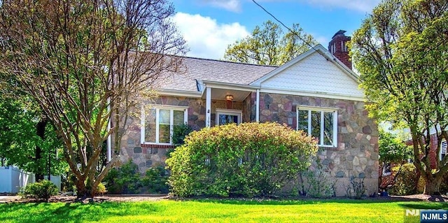 bungalow-style home with a chimney, stone siding, and a front yard