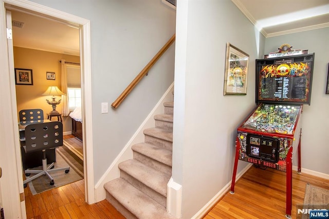 stairway with baseboards, crown molding, and wood finished floors