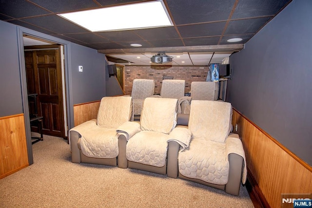home theater room with carpet flooring, wooden walls, and wainscoting