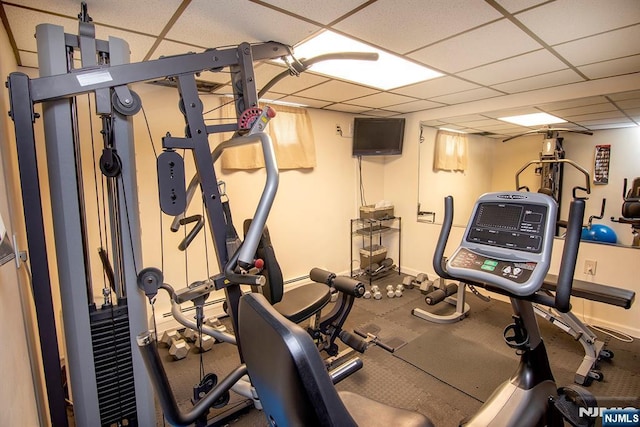 exercise room with a paneled ceiling and baseboards