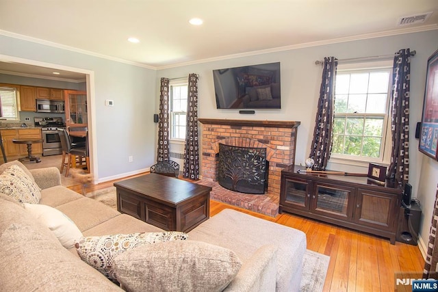 living area featuring light wood-style flooring, recessed lighting, ornamental molding, visible vents, and a fireplace