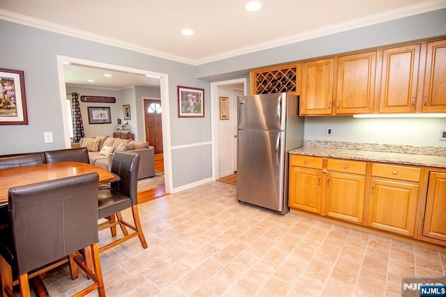 kitchen featuring freestanding refrigerator, light stone countertops, recessed lighting, baseboards, and ornamental molding